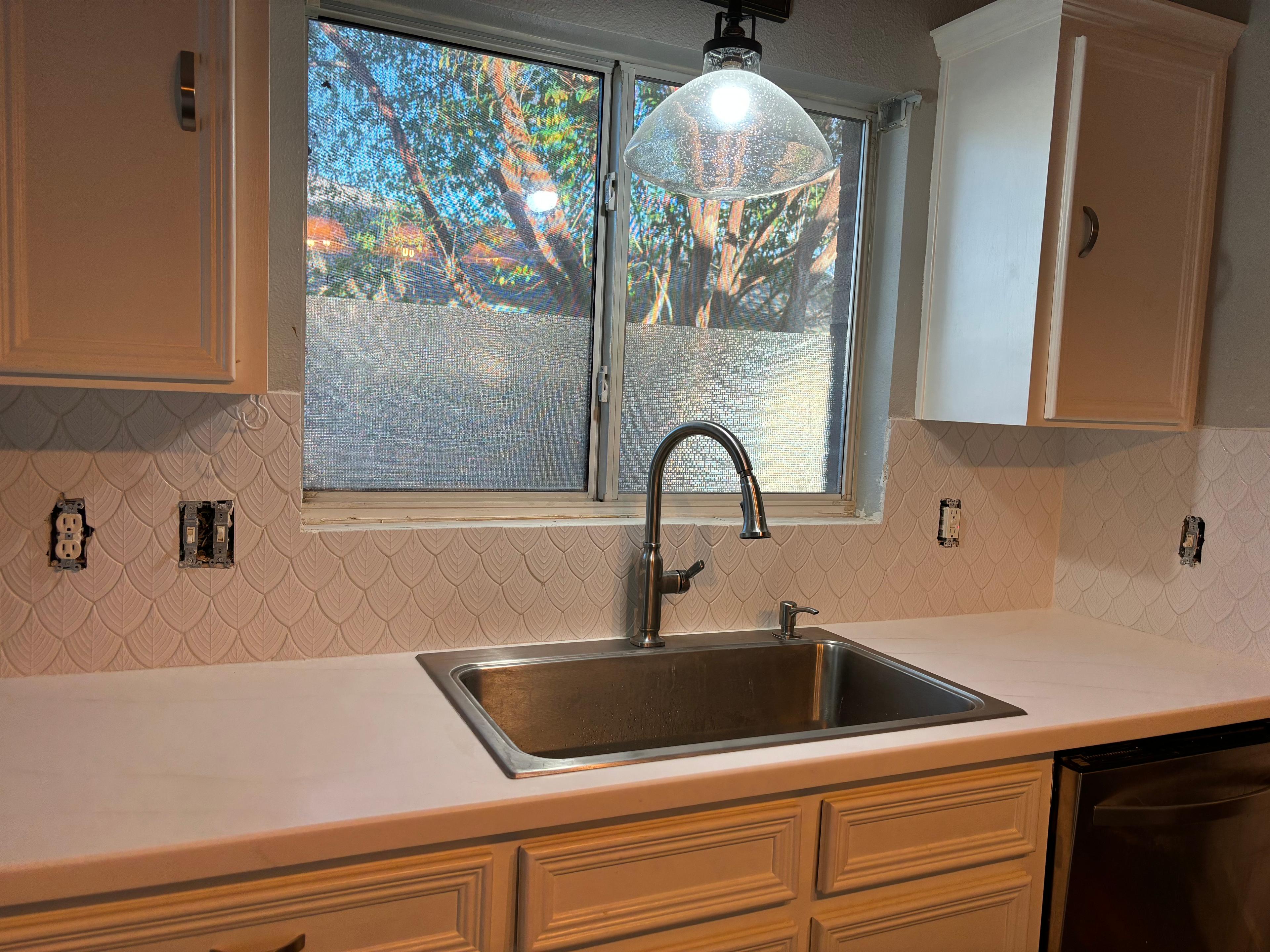 Scalloped tile backsplash installed around a kitchen sink and window