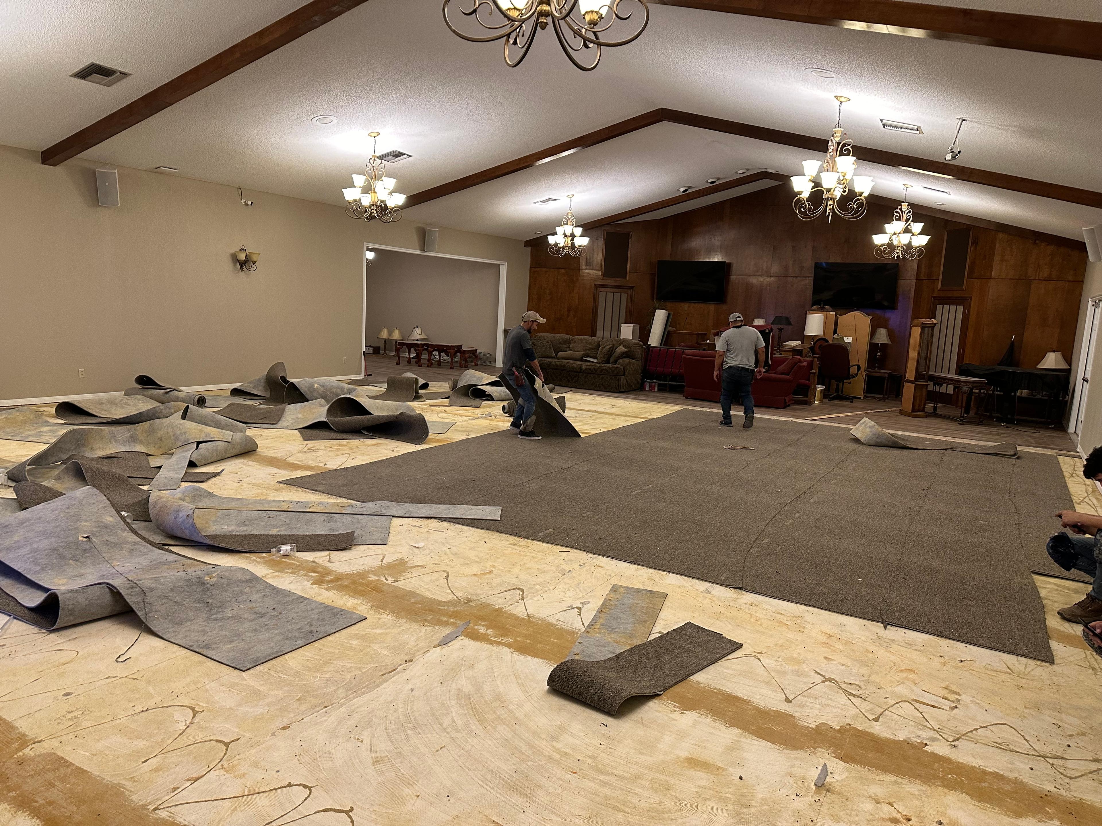 Crew rolling up old carpet to expose the subfloor before new flooring goes in