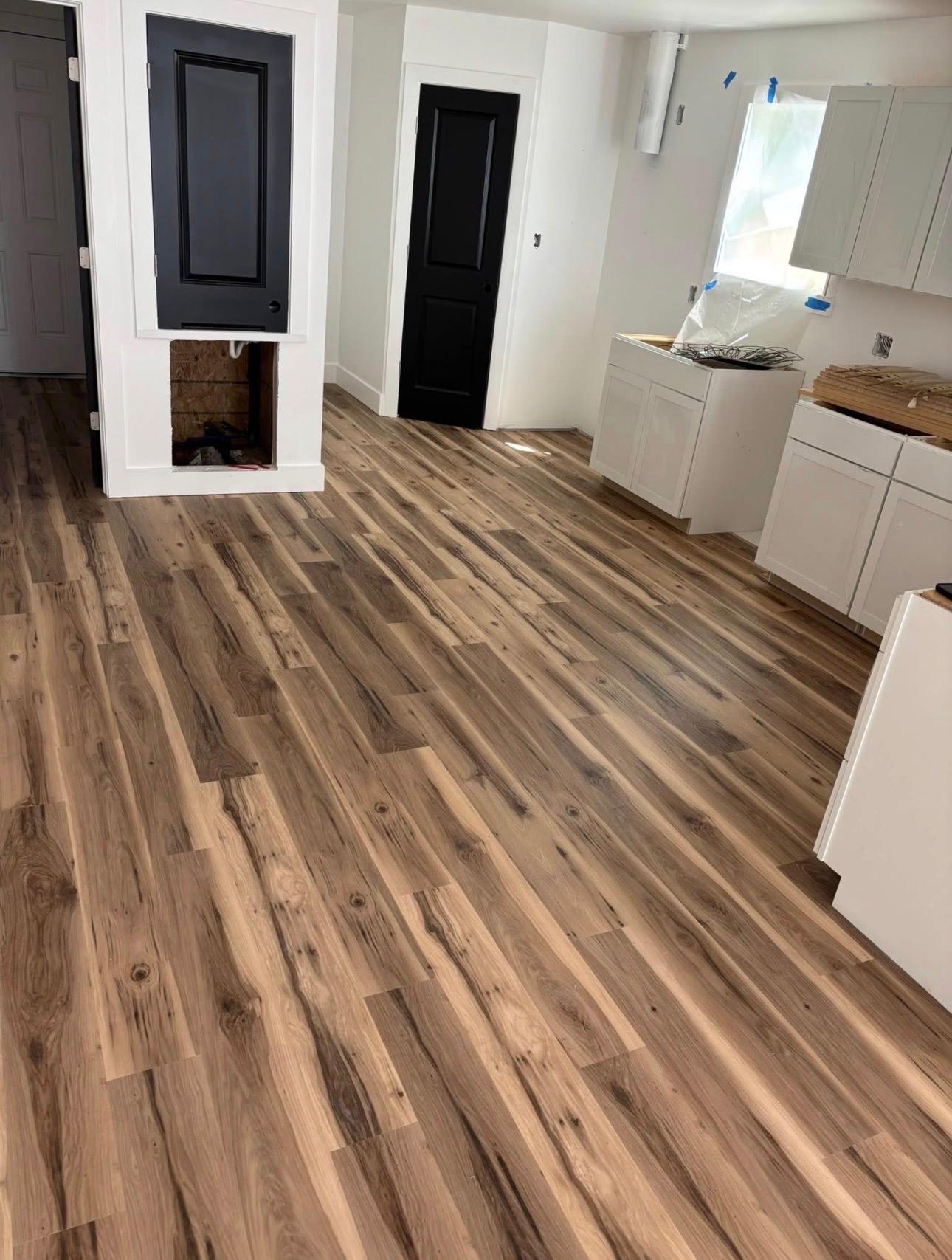 Wide-plank wood-look flooring installed through an open kitchen and living area