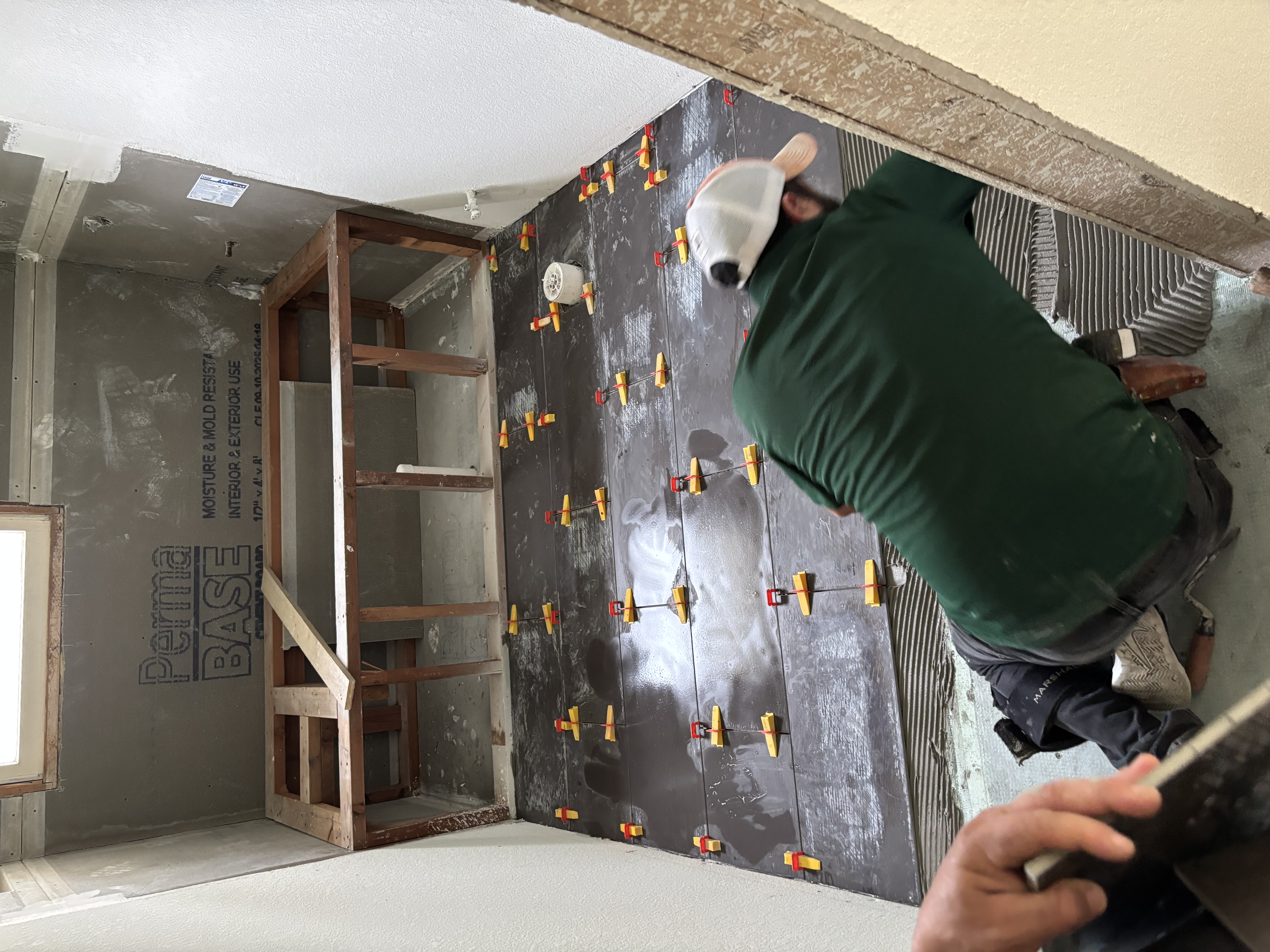 A Gutierrez Flooring installer setting large-format tile on the floor during a remodel.