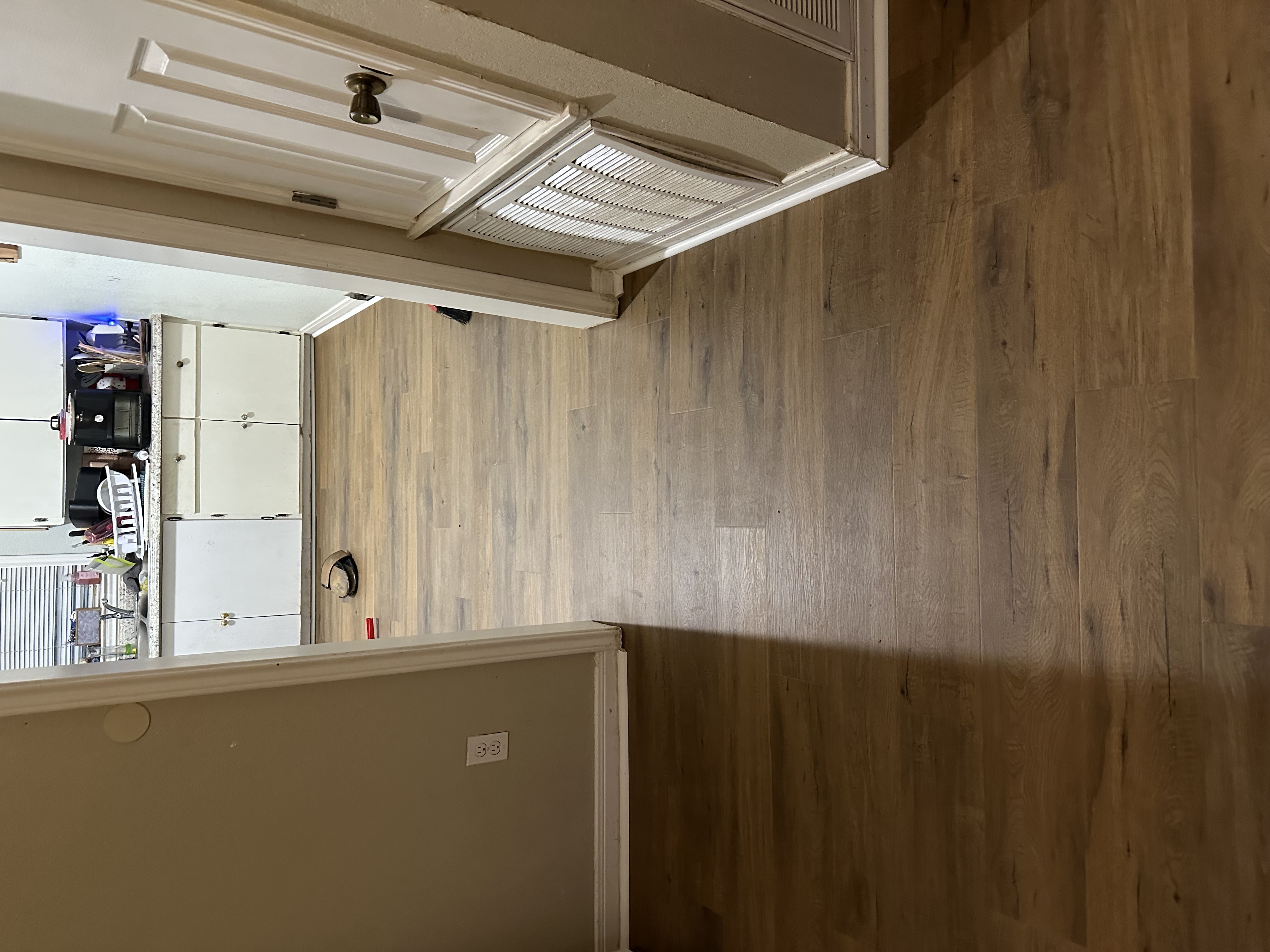 Warm wood-look luxury vinyl plank flooring newly installed across an open kitchen and dining area